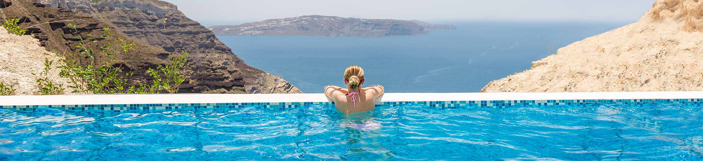 Frau im Infinity Pool mit Blick auf's Meer